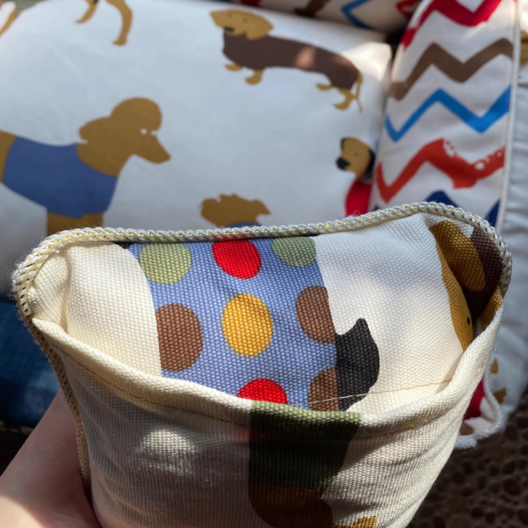 Sofa Dog Bed – Washable, Anti-Chew, Ultra Soft & Detachable Fabric pouch with colorful polka dot pattern held in front of patterned cushions.