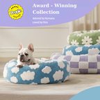 CozyPaw Donut Dog Bed – Modern Design, Soft & Warm, Washable Dog lying on a blue cloud-patterned pet bed with other beds in the background, featuring an 'Award-Winning Collection' label.