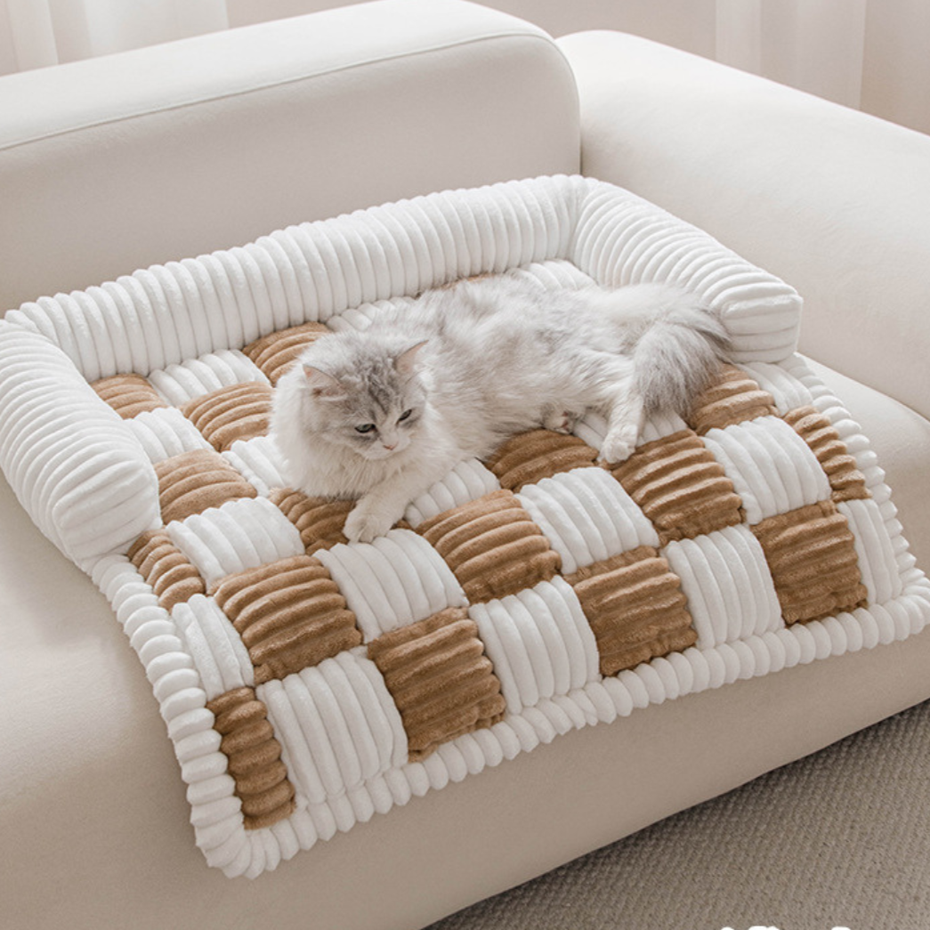 Fluffy Fuzzy Calming Dog Bed Sofa Protector Pet Mat Cat lying on a checkered pet bed in a cozy living room.