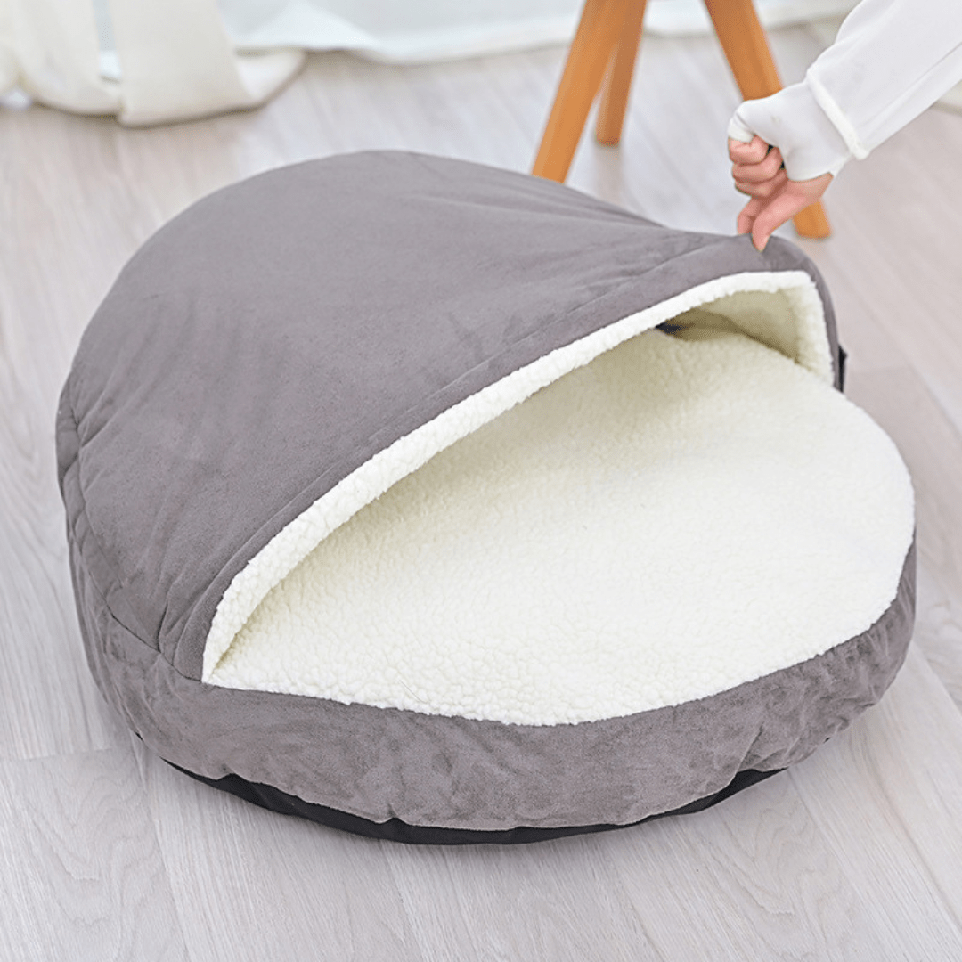 Calming Ultimate Anti-Anxiety Dog Bed – Cozy Hooded BedGray pet bed with white interior on a light wooden floorJoypup